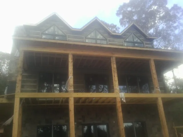 Dormers and porch framing on a large log home under construction — Roof Coating work by our crew in Spring Valley